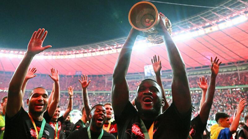 Neues Image: Bayer will Bayern auf Dauer Paroli bieten Leverkusens Victor Boniface (r) hält den Pokal jubelnd hoch, während seine Teamkollegen feiern.