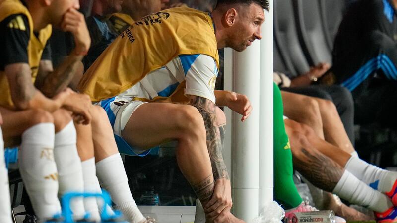 Lionel Messi fasst sich an den geschwollenen verletzten rechten Knöchel.