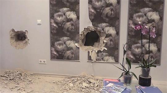 Löcher sind in der Wand in einem Friseurladen zu sehen. Unbekannte brachen in den Salon ein und beschädigten eine Wand zur benachbarten Bankfiliale.