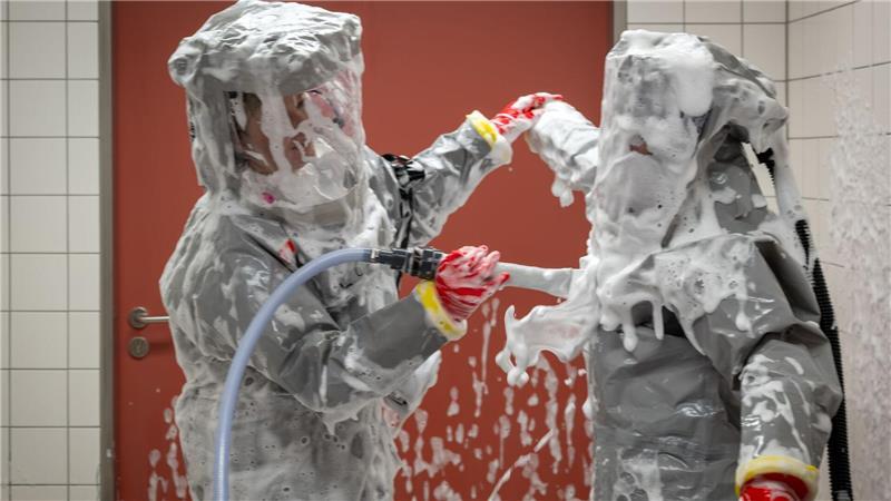 Louise Götze (l) und Ursula Pfitzner, Intensivpflegerinnen und Koordinatorinnen auf der Sonderisolierstation der Charité, desinfizieren sich während eines Pressetermins nach der Rückkehr aus dem Patientenzimmer in der Schleuse mit einer Schaumlösung.