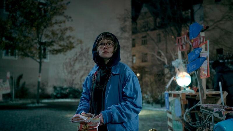 Luise Kogan (Lea Drinda) verteilt Flyerin einer Szene der Serie „Wer wir sind“.