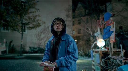 Luise Kogan (Lea Drinda) verteilt Flyerin einer Szene der Serie „Wer wir sind“.