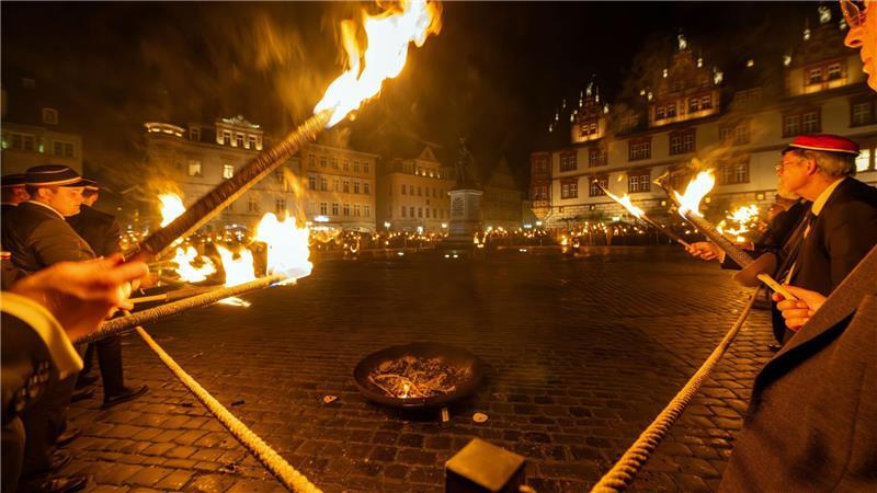 Männer stehen mit Fackeln rund um den Coburger Marktplatz.