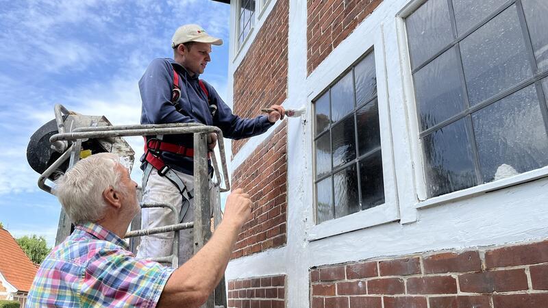 Maler Stefan Koppelmann-Hilck vom Malereibetrieb Adami tauscht sich mit Kirchenvorstand Wilfried Heinsohn über den Stand der Sanierungsarbeiten am Fachwerk von St. Marien in Grünendeich aus.