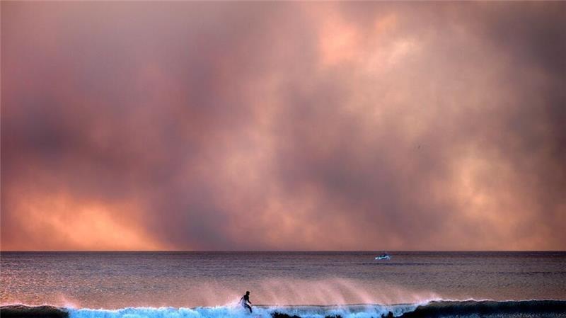 Manchen lassen die Waldbrände in auch Kalifornien kalt: Dieser Surfer reitet auf einer Welle, während Rauch den Himmel verdunkelt.