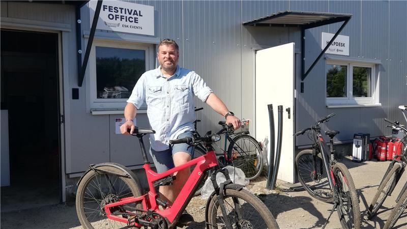 Marc Engelke ist mit seinem roten E-Mountainbike auf dem Festivalgelände unterwegs.