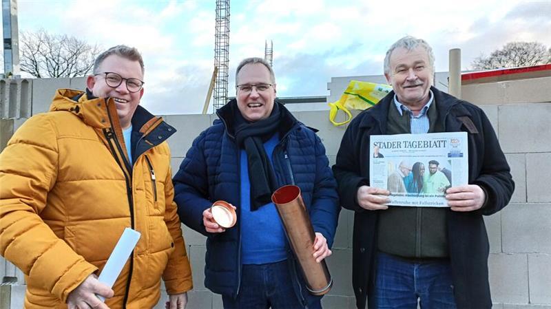 Marcus Finke vom Fachbereich Bauen (von links), Samtgemeindebürgermeister Matthias Hartlef und Deinstes Bürgermeister Jörg Müller bestücken die Zeitkapsel.