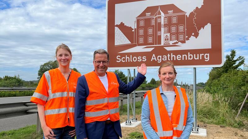 Geister-A26-Anschlussstelle Buxtehude: So geht es mit der Rübker Straße weiter Maren Quast von der Autobahn GmbH weiht gemeinsam mit Landrat Kai Seefried und Kreisbaurätin Madeleine Pönitz das touristische Hinweisschild für das Schloss Agathenburg an der A 26 ein (von links).