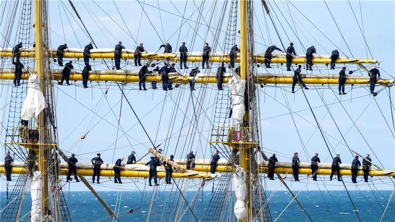 Marinesoldaten stehen bei der Ausfahrt aus dem Hafen Warnemünde an den Rahen auf dem Segelschulschiff Gorch Fock. 