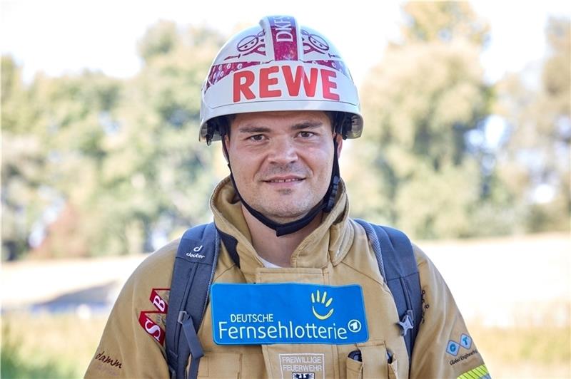 Mario Schnepf, Berufsfeuerwehrmann, steht in feuerfester Kleidung, inklusive Schutzhelm am Straßenrand. Der Feuerwehrmann will zu Fuß von Hamburg nach Sömmerda in Thüringen laufen. Foto: Wendt/dpa