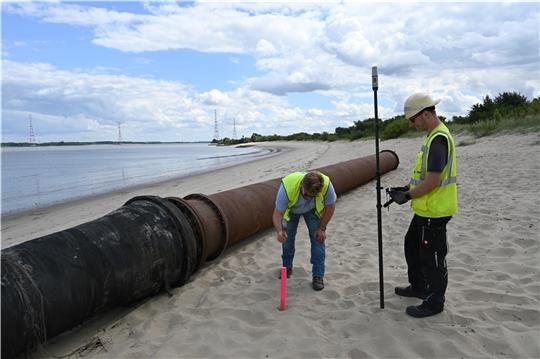 Markus Kröncke vom Ingenieurbüro Geo-Group und DEME-Projektingenieur Florian Lesch vermessen den Strand in Bassenfleth für die Ufervorspülung. Diese startet in dieser Woche im südlichen, abgesperrten Teil (von rechts).
