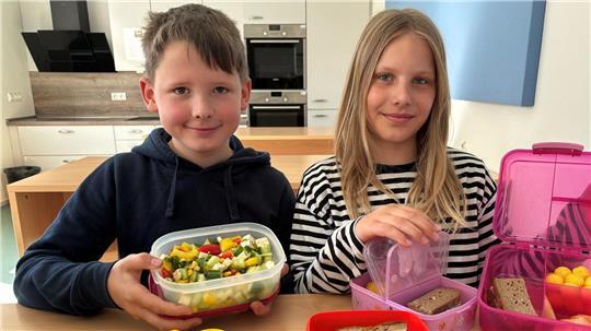 Marlon Uhl und Laura Weddemann zeigen ihre Brotdosen. Die Grundschüler haben Wurstbrot, Obst und Salat, aber auch etwas Süßes dabei.