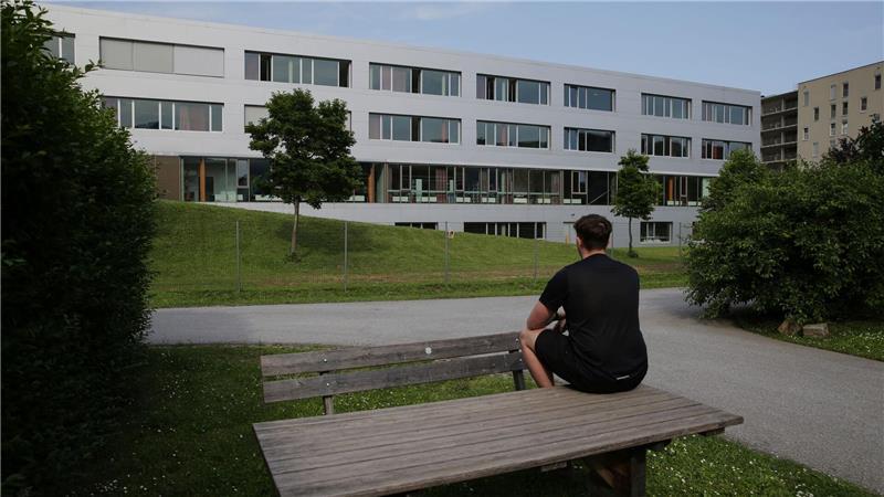 Marvin sitzt auf einem Tisch vor einem Schulgebäude und betet für die Opfer des Amoklaufs an einem Gymnasium. Ein 21-Jähriger hatte neun Menschen getötet und danach Suizid begangen.
