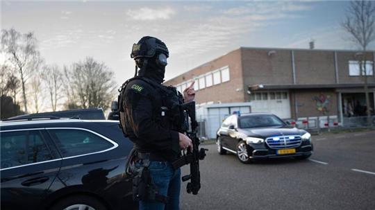 Maskierte und bewaffnete niederländische Polizisten bewachen einen Transport mit einigen der Verdächtigen, die vor dem Hochsicherheitsgebäude des Gerichts in Amsterdam eintreffen.