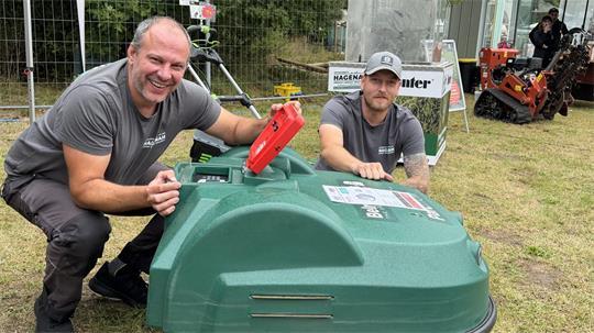 Matthias Braack und Jannik Hagenah mit dem großen Mähroboter, der auch Golfbälle aufsammelt.