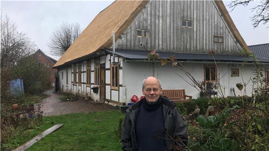 Matthias Schlüter vor seinem Reetdachhaus mit frisch gedecktem Dach.