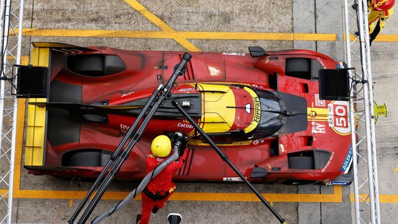 Mechaniker betanken das Auto des Teams Ferrari.