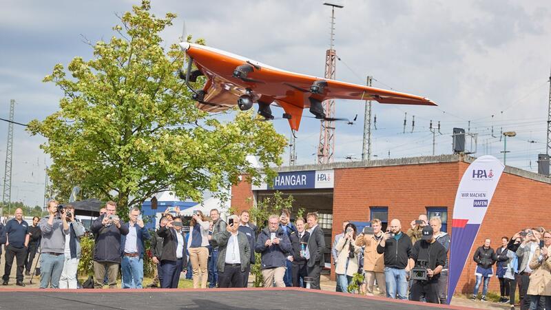 Medienvertreter und Gäste beobachten den Start einer „CarryAir“-Drohne anlässlich der Eröffnung des „dronePORTs“ am Kleinen Grasbrook.