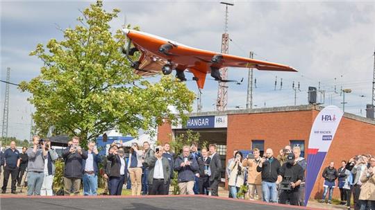 Medienvertreter und Gäste beobachten den Start einer „CarryAir“-Drohne anlässlich der Eröffnung des „dronePORTs“ am Kleinen Grasbrook.