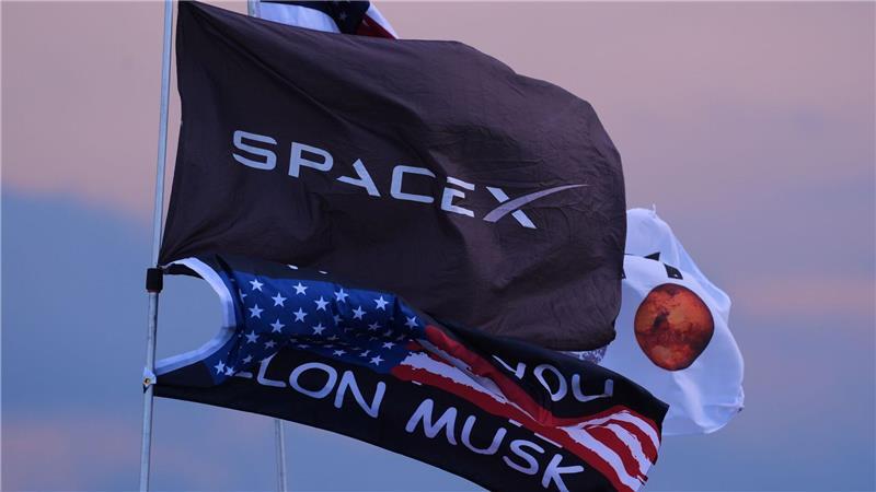 Zehnter Testflug von Rakete Starship um einen Tag verschoben Mehrere Fahnen, darunter zwei mit dem Aufdruck SpaceX und Elon Musk, sind in der Nähe des Startortes.