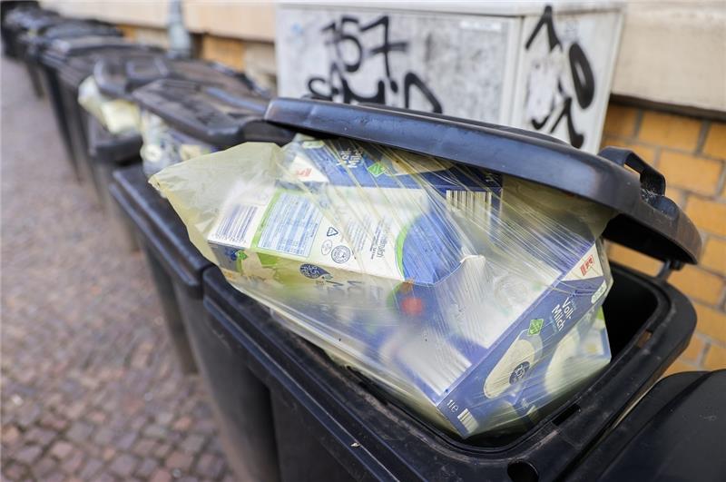 Mehrere volle Restmülltonnen, die zudem noch falsch befüllt sind, stehen an einer Hauswand.  Foto: Jan Woitas/dpa-Zentralbild/dpa