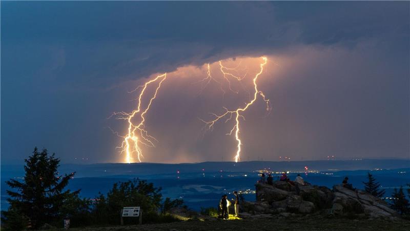 Menschen beobachten Blitze eines Gewitters am Großen Feldberg im Taunus.