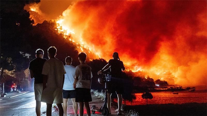 Waldbrand an der Adria: ein Toter, Verletzte, Zerstörungen Menschen beobachten am frühen Freitag, dem 14. August 2026, einen Waldbrand an der Adriaküste in der Nähe von Omis im Süden Kroatiens.