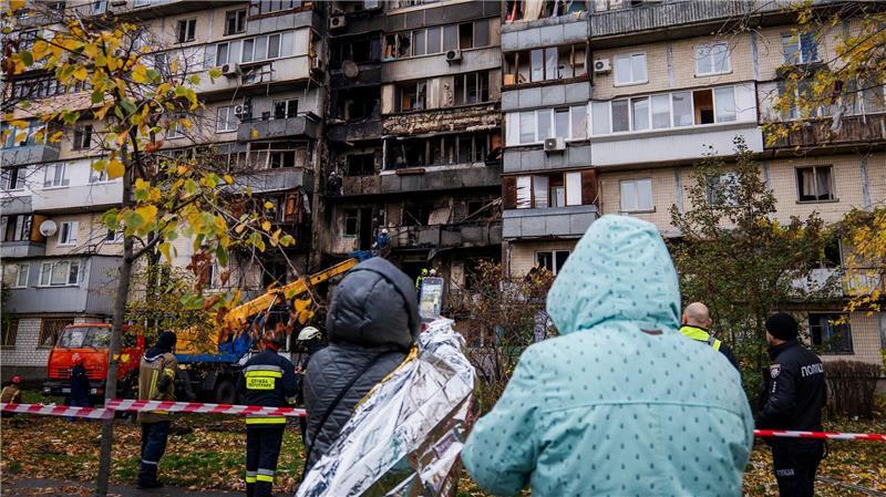 Menschen beobachten die Arbeit der Feuerwehr in einem zerstörten Wohnhaus nach einem russischen Drohnenangriff.