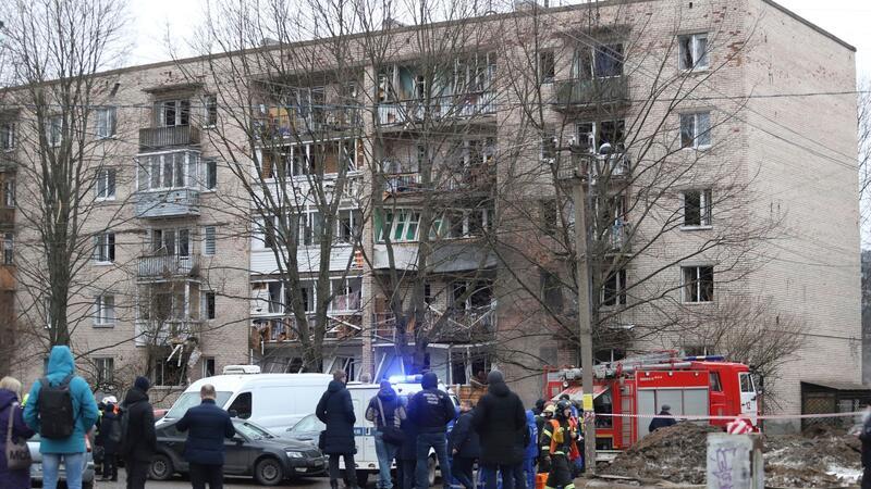 Krieg gegen die Ukraine: So ist die Lage Menschen beobachten, wie Rettungskräfte nach einer Explosion an der Seite des beschädigten Wohnhauses in Sankt Petersburg arbeiten.