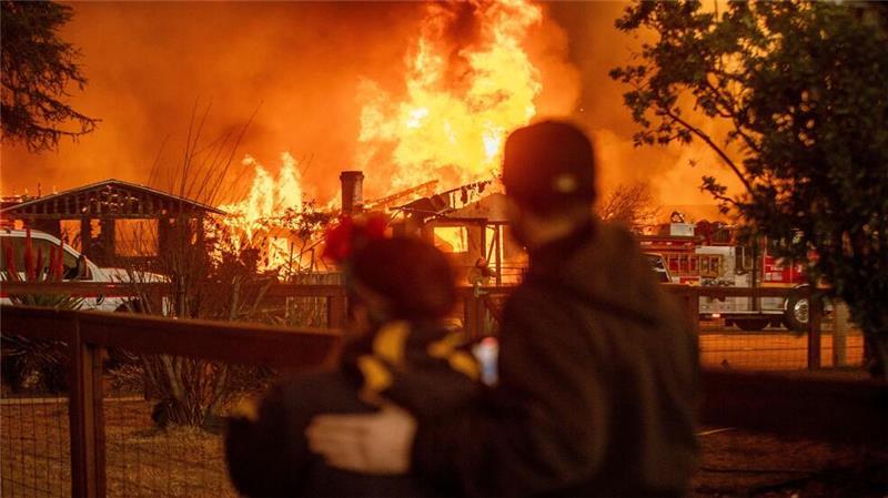 Menschen beobachten, wie das Eaton-Feuer in Los Angeles ein Gebäude verschlingt.