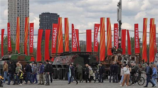 Menschen besichtigen eine Schau zu Kriegstrophäen im Park Pobedy (Park des Sieges) in Moskau. Gezeigt wird Militärtechnik aus verschiedenen westlichen Ländern und der Ukraine. Im Hintergrund zu sehen sind rote Fahnen mit der Aufschrift Pobeda! (auf Deutsch: Sieg).