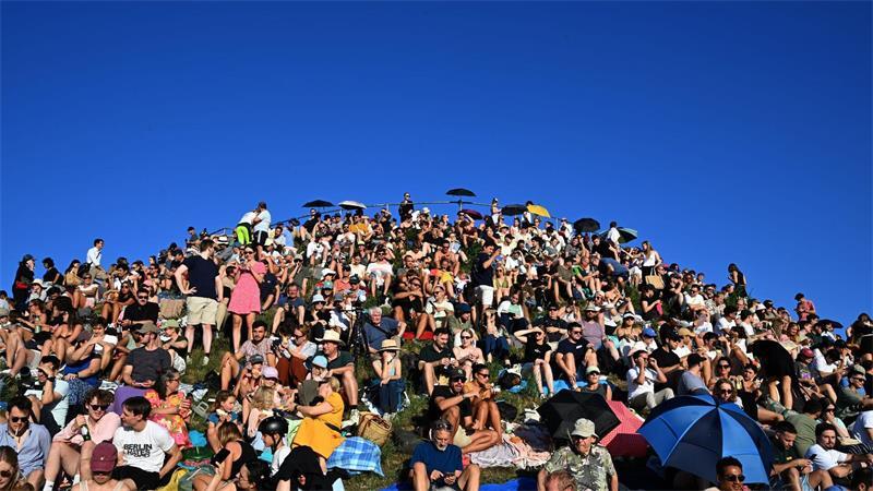 Menschen betrachten eine partielle Sonnenfinsternis am Olympiaberg im Münchner Olympiapark. 