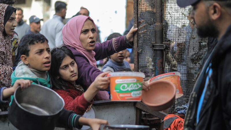 Menschen bitten an einer Essensausgabe in Rafah um Lebensmittel.
