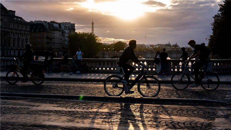 Bilder des Tages Menschen fahren bei Sonnenuntergang mit dem Fahrrad auf einer Brücke über die Seine in Paris.