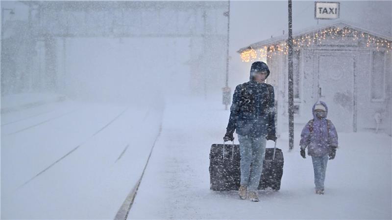 Menschen gehen bei starkem Schneefall am Bahnhof in der Stadt Åre in Schweden, nachdem der Zugverkehr eingestellt wurde. 