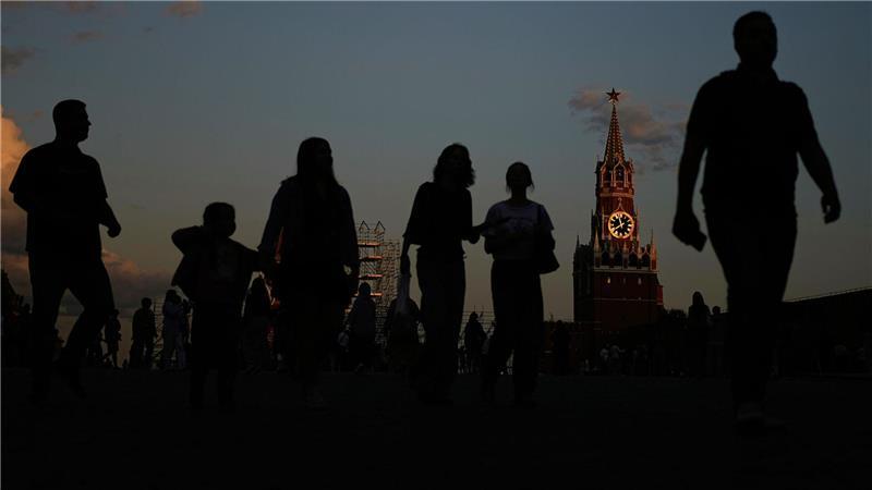 Bilder des Tages Menschen gehen über den Roten Platz, während das Sonnenlicht von der Kreml-Uhr auf dem Spasskaja-Turm des Kremls reflektiert wird.