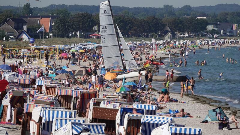 Menschen genießen das Sonnenwetter am Strand der Ostsee.