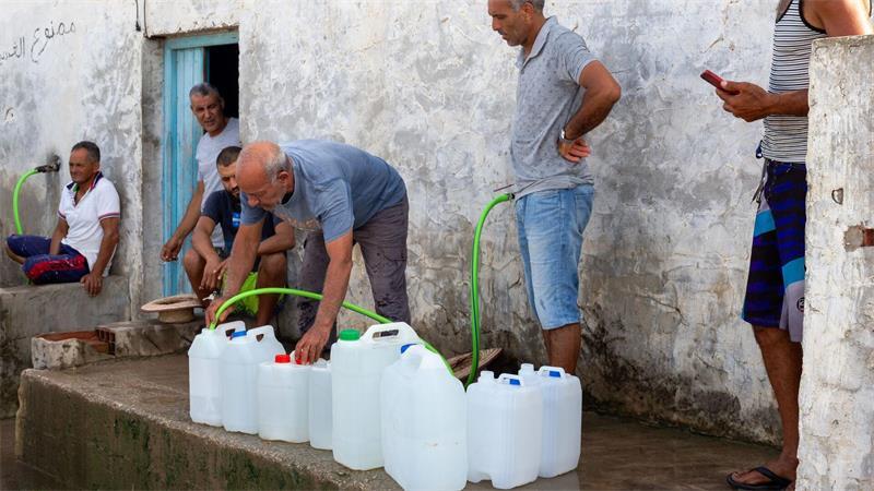 Menschen in Tunesien befüllen Wasserbehälter mit Trinkwasser.
