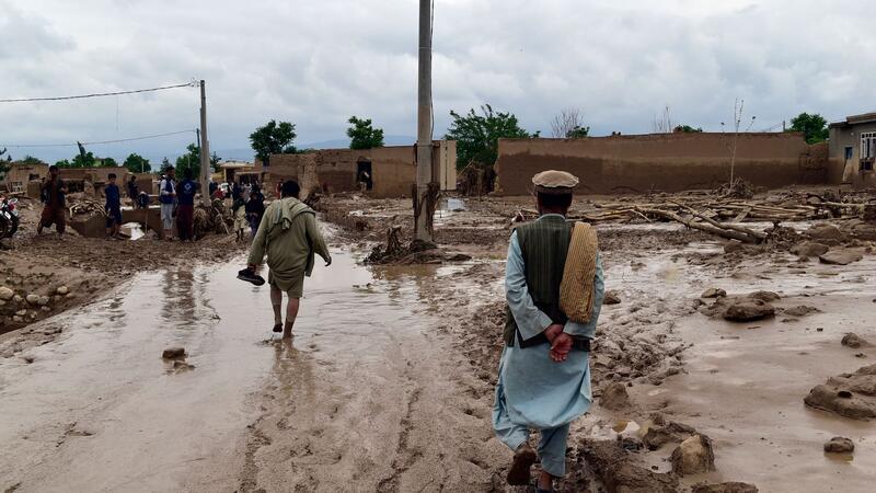 Menschen in der Nähe ihrer beschädigten Häuser nach Überschwemmungen in der nordafghanischen Provinz Baghlan.