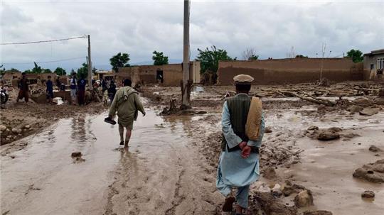 Menschen in der Nähe ihrer beschädigten Häuser nach Überschwemmungen in der nordafghanischen Provinz Baghlan.