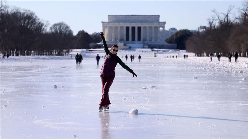 Menschen laufen Schlittschuh auf dem zugefrorenen Wasserbecken vor dem Lincoln Memorial.