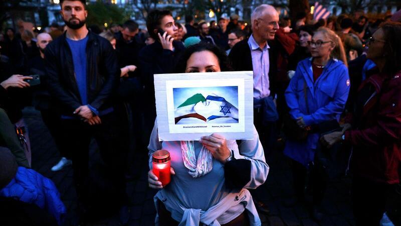 Menschen nehmen vor der Synagoge am Berliner Fraenkelufer an einer Mahnwache teil.