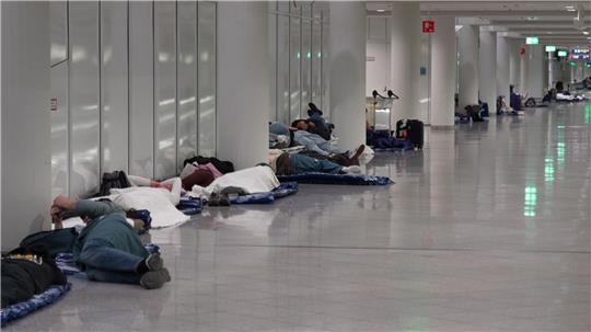 Menschen ruhen sich nach möglichen Drohnensichtungen am Flughafen München aus. 