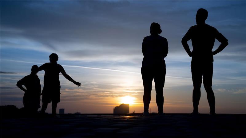 Bilder des Tages Menschen schauen sich am frühen Morgen den Sonnenaufgang auf dem Olympiaberg an.