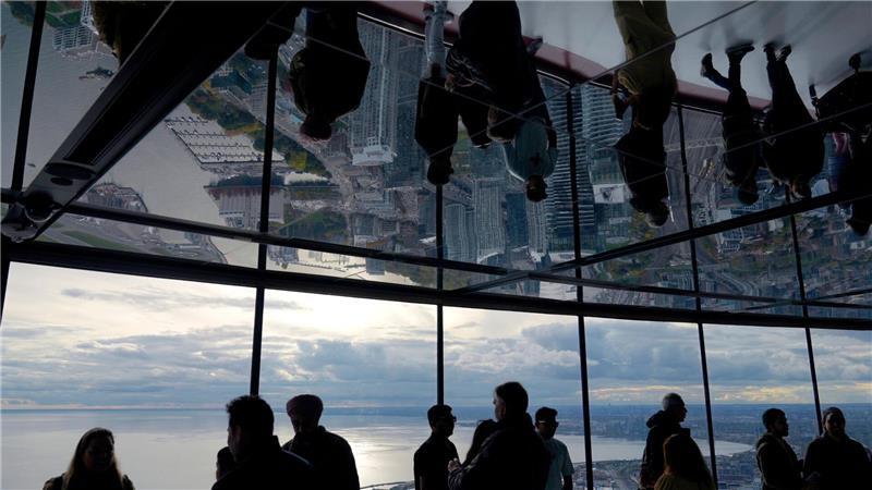 Menschen schauen vom CN Tower in Toronto auf das Rogers Centre und den Ontariosee.