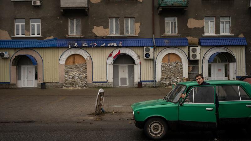 Malta-Konferenz: Kiew sieht Rückhalt für Friedensformel Menschen schieben ein liegengebliebenes Fahrzeug an einem stillgelegten Restaurant vorbei.
