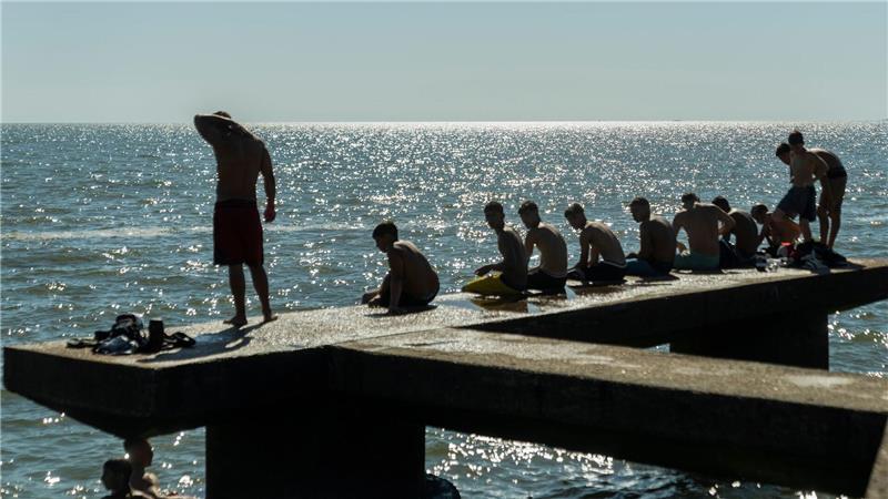 Menschen sitzen auf einem Dock in Montevideo.