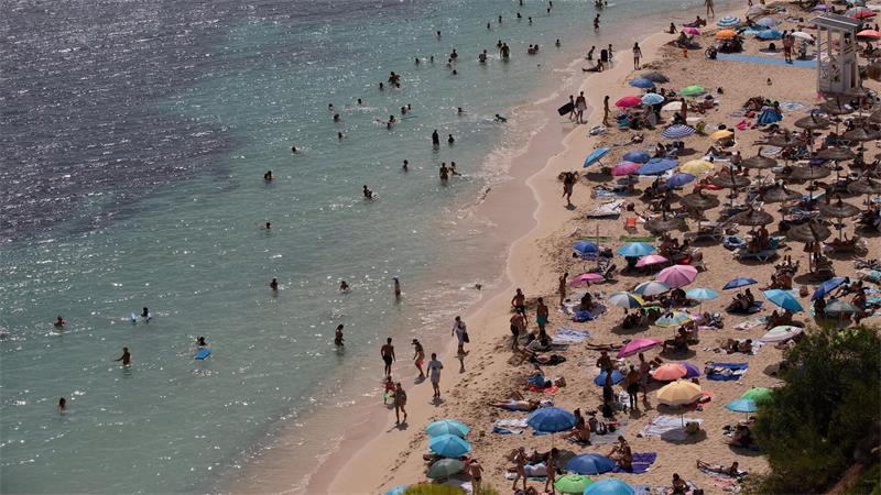 Menschen sonnen sich und entspannen am Meer am Strand von Caleta de Portals Nous auf Mallorca.