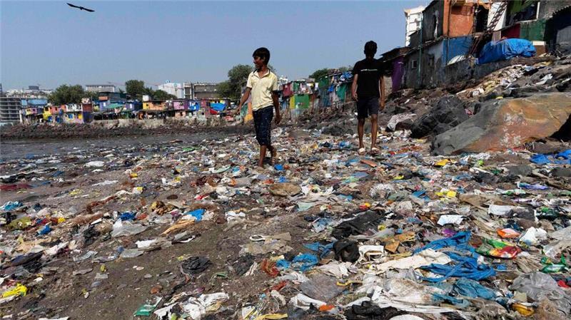 Menschen spazieren am Strand des Badhwar Park im indischen Mumbai an Plastikmüll vorbei. (Archivbild)
