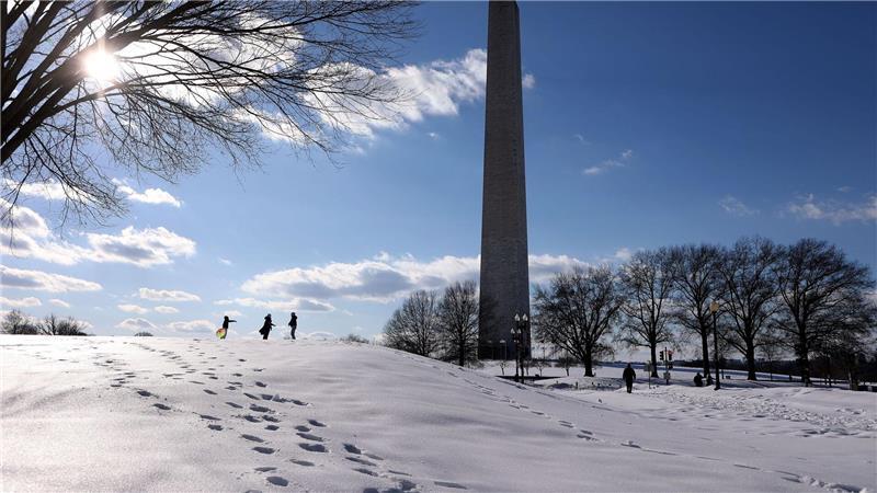 Menschen spazieren im Schnee auf der National Mall.